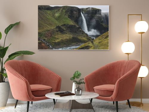 icelandic landscape with Haifoss waterfall and green hills on misty day