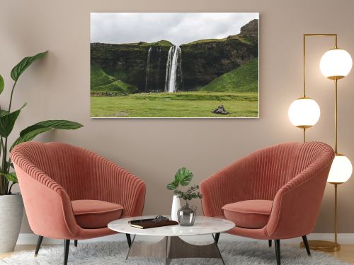 ICELAND - 20 JUNE 2018: beautiful waterfall Seljalandsfoss and tourists under cloudy sky 