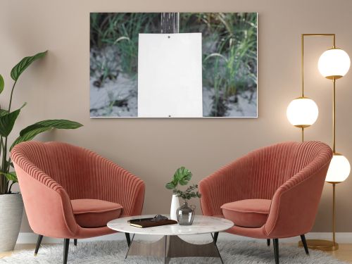 A stark white blank sign stands tall on a 4x4 post, anchored in the pristine white beach sand of Port St. Joe, with blurred coastal vegetation softening the background.