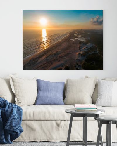 Cinematic 4K aerial drone footage captures Miramar Beach dunes at sunrise in Ciudad Madero, Tamaulipas. Warm orange and golden light paints the sky and reflects on the calm sea as the coastline stretches to the horizon. Palapas line the shore while A