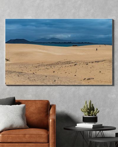 Spain, Canary Islands, Fuerteventura-February 5, 2026: Golden sand dunes stretch toward blue ocean and volcanic mountains beneath cloudy sky, forming dramatic coastal desert landscape.