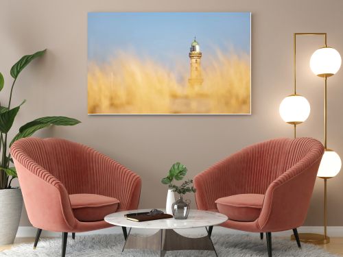 Lighthouse in Warnemuende, Germany behing the blurred marram grass, on sand dunes. High quality photo