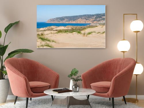 Soft sand dunes with sparse grass leading toward the Atlantic Ocean horizon near Guincho Cascais Portugal.