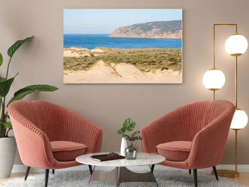 Expansive sand dunes and coastal vegetation with a wide view of the Atlantic Ocean near Guincho Cascais Portugal.