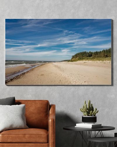 Coastal area in Lithuania Coastal scenery with sandy beach, dunes with marram grass and rough sea on a clear summer day with blue sky.