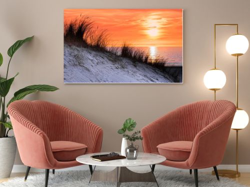 Orange sunset in evening with dune and sea at coast in netherlands