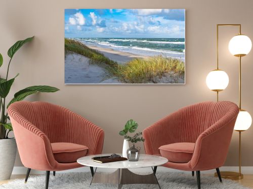 Rough sea with waves in autumn or winter, sandy beach and dunes with reeds and dry grass in the morning