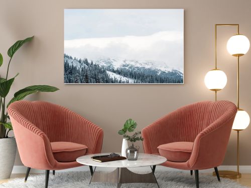 scenic view of snowy mountains with pine trees and white fluffy clouds