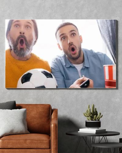 excited interracial father and son watching football championship at home, banner