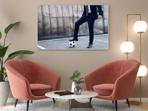 partial view of businessman in suit playing soccer on street