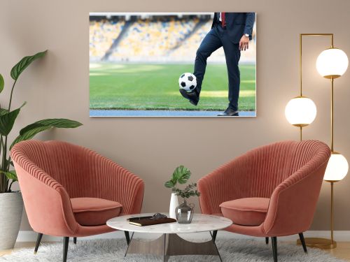 cropped view of young businessman in suit playing with soccer ball at stadium