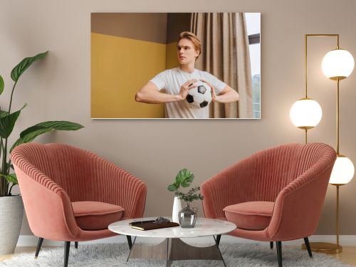 young handsome man holding football at home, end of quarantine concept