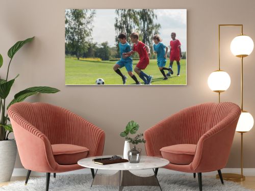 four multicultural kids playing football on grass  