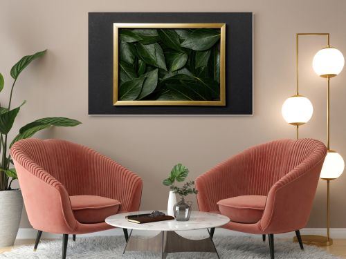 top view of golden frame with green leaves inside on black background
