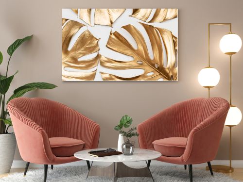 Artistic arrangement of real monstera leaves painted with gold paint on white background. Creative tropical pattern. Luxury summer concept.