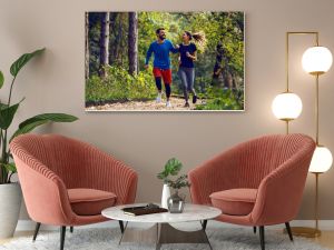 Pełna długość, dopasowana, sportowa, szczęśliwa para kaukaska w odzieży sportowej biegająca rano po lesie na szlaku