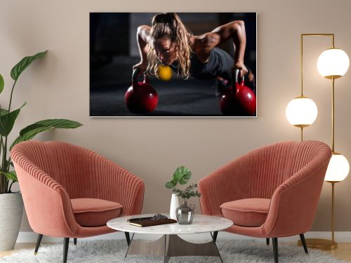 Woman athlete exercising with kettlebells indoors