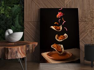 Creative food image of Mexican Tacos de Cochinita Pibil and onion with habanero chili falling on traditional mexican clay dish. Levitation photography.