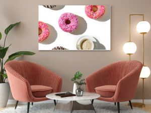 A cup of coffee and a variety of donuts on a white background. Flat lay composition with coffee and donuts.