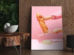 Female hands grating bread, baguette to make breadcrumb for meat isolated over pink background