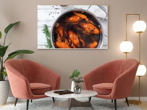 cooked crawfish in saucepan with lemons and spices on wooden background