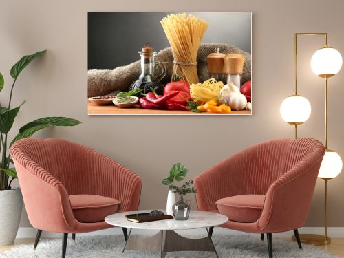 Pasta spaghetti, vegetables and spices, on wooden table, on grey background