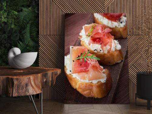 Baguette with cottage cheese, arugula and ham, sandwich on a board, selective focus. Wooden rustic background. Top view