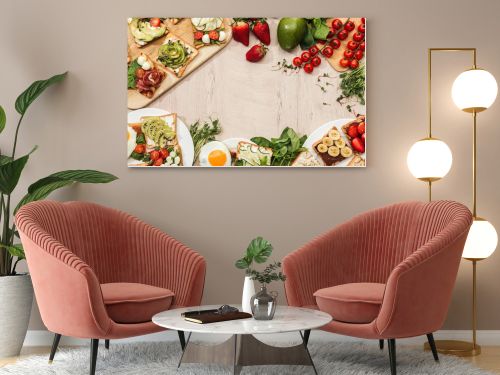 top view of toasts with vegetables, fruits and prosciutto with greenery and ingredients on wooden table