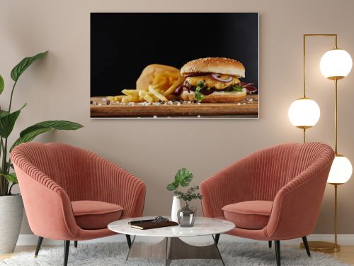 salt, french fries and delicious burger with meat on wooden surface isolated on black