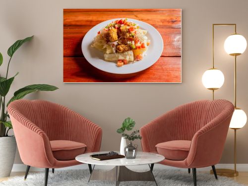 Traditional chicharron dish with cassava and tomato salad. Latin food chicharron con yuca served on wooden table. Nicaraguan dish chicharron with cassava on the table.