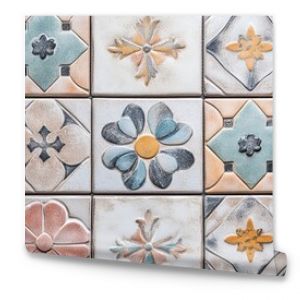 Top view of a decorative tile pattern with a mix of floral and geometric designs in pastel colors, arranged on a kitchen backsplash