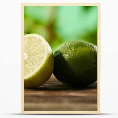 panoramic shot of cut and whole limes on wooden surface 