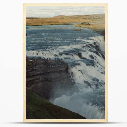 group of tourists looking at majestic waterfall in Iceland 