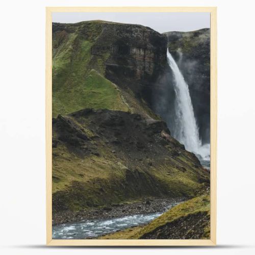icelandic landscape with Haifoss waterfall and green hills on misty day