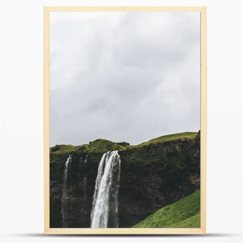 scenic view of landscape with Seljalandsfoss waterfall in highlands under cloudy sky in Iceland 