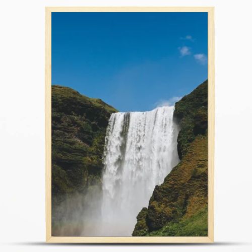 scenic view of waterfall Skogafoss against bright blue sky in Iceland