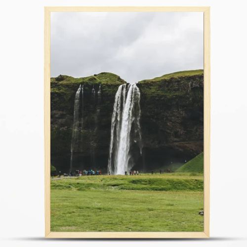 ICELAND - 20 JUNE 2018: beautiful waterfall Seljalandsfoss and tourists under cloudy sky 