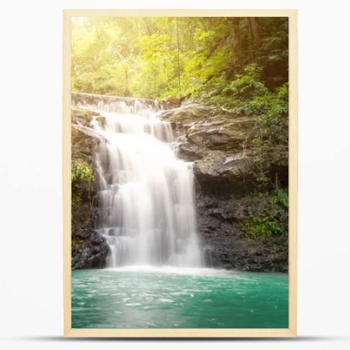 Small waterfall with water splashing and tumbling over the rocks in the forest on a bright sunny