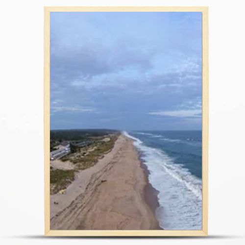 Drone panorama of Napeague on Long Islands South Fork, showing Atlantic Ocean surf, sandy beach, dunes and a beachfront resort complex at dusk.