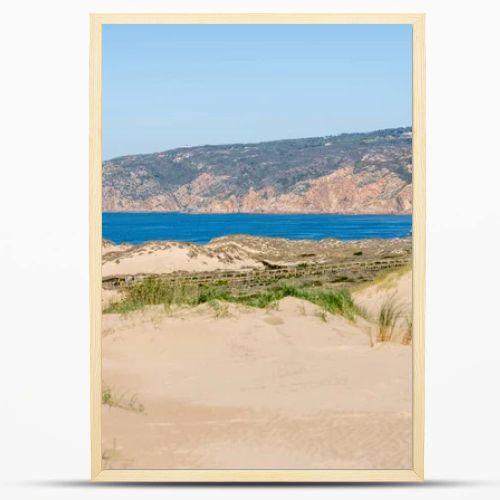 Soft sand dunes with sparse grass leading toward the Atlantic Ocean horizon near Guincho Cascais Portugal.
