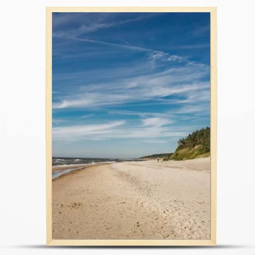 Coastal area in Lithuania Coastal scenery with sandy beach, dunes with marram grass and rough sea on a clear summer day with blue sky.