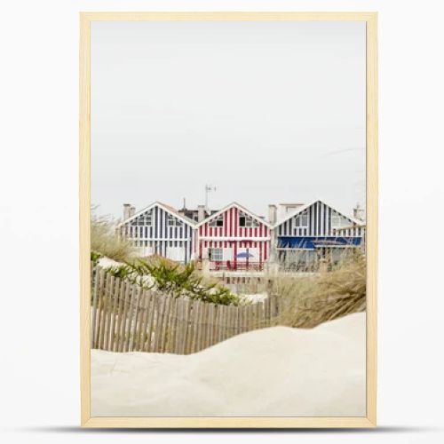 Idyllic and quaint beach houses seen from beach dunes. Beach houses with colorful stripes from Costa Nova, Portugal.