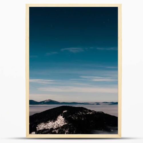 scenic view of snowy mountains with pine trees and white fluffy clouds in dark sky in evening