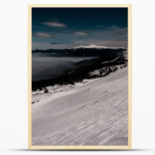 scenic view of snowy mountains with pine trees and white fluffy clouds in dark sky in evening