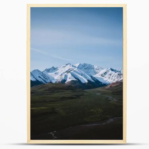 Capture the majestic beauty of snowcapped Alaskan mountains with a winding river valley. Perfect for themes of nature, adventure, and tranquility, showcasing the untouched wilderness of Alaska.