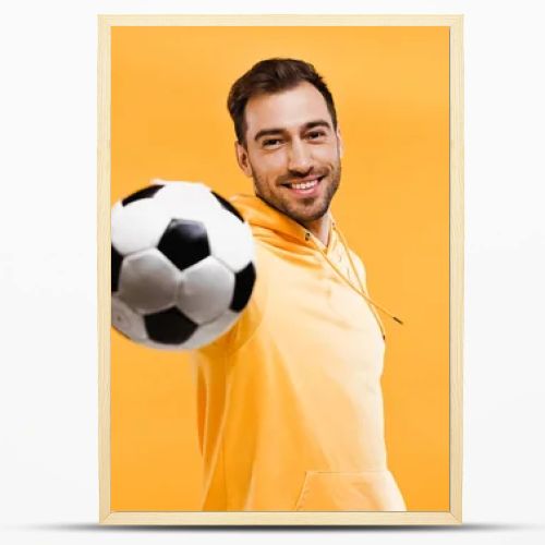 smiling man playing with football isolated on yellow