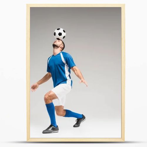 Sportsman holding football on head while balancing on grey background 