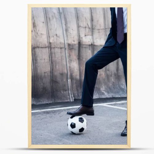 partial view of businessman in suit playing soccer on street