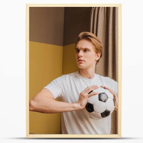 young handsome man holding football at home, end of quarantine concept