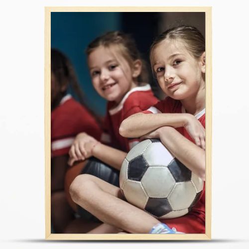 Smiling girl with soccer ball  in good mood  before training  in changing room.